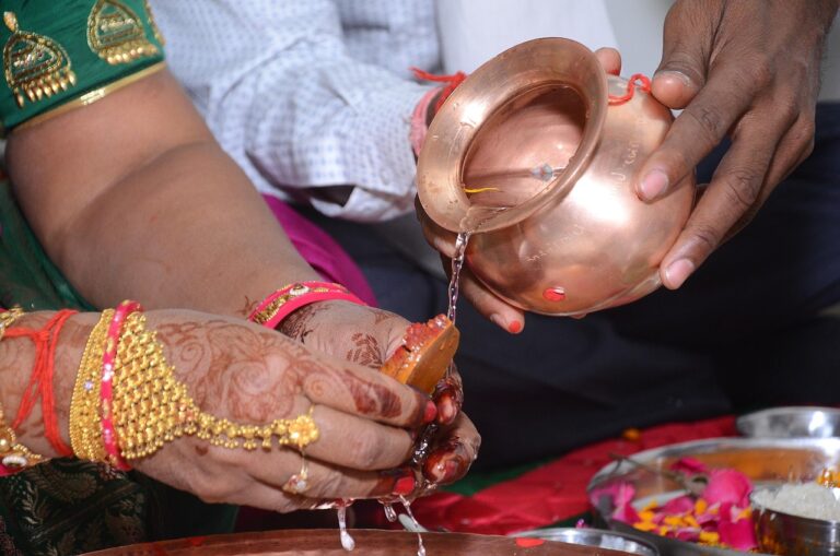 Decorative engagement rings holder ideas with henna hands as water is poured over a ring tray with flowers and rice
