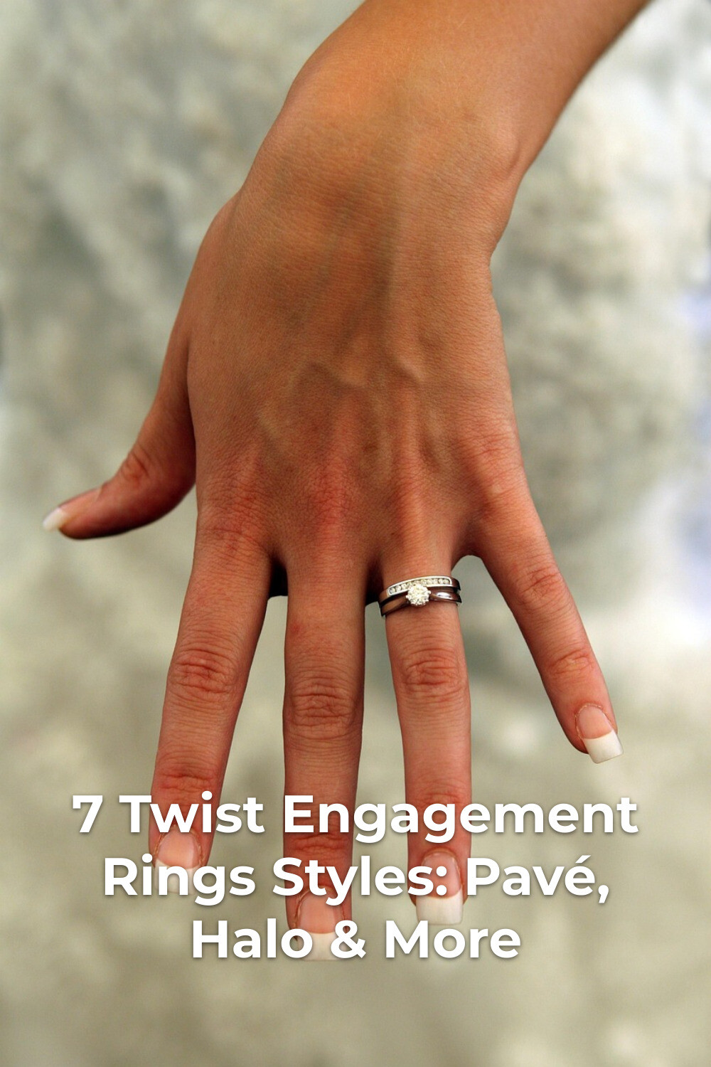 Twist engagement rings on hand with white tipped nails, ring finger close-up against a soft blurred background