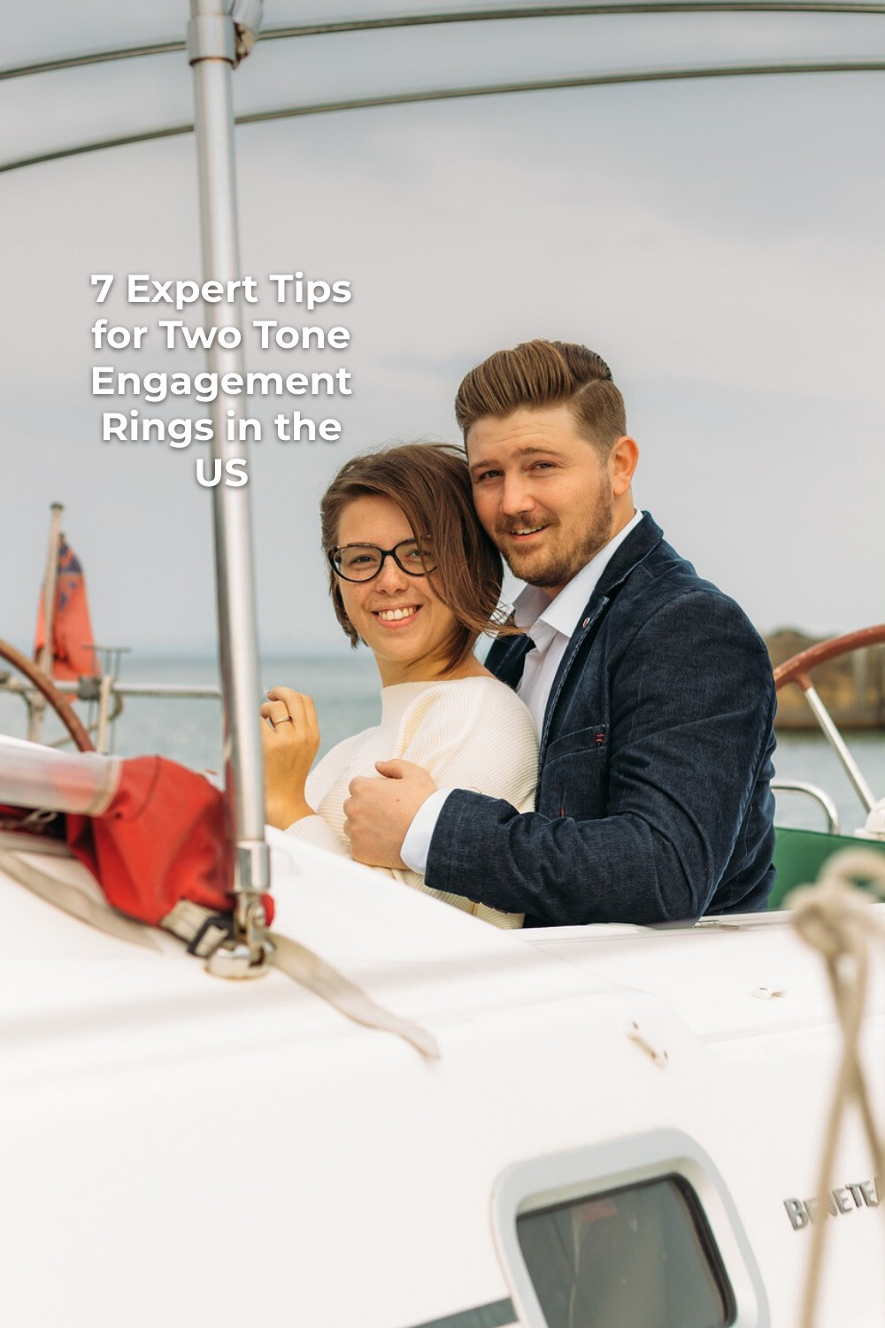 Two tone engagement rings moment as a couple hugs on a boat with calm water behind them