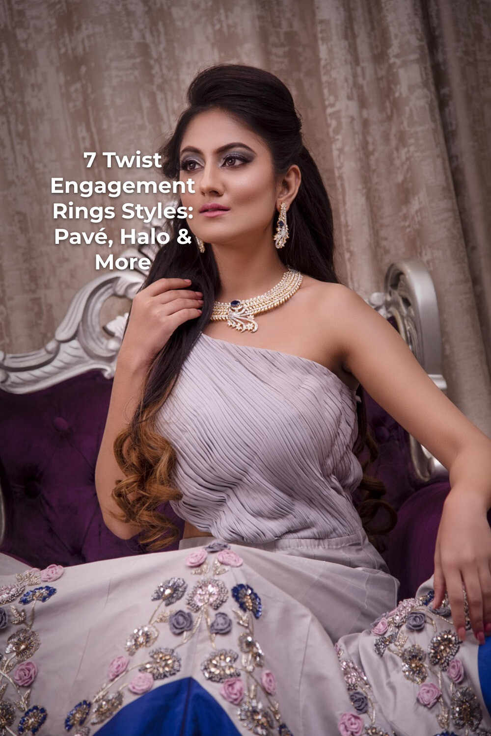 Woman in strapless embroidered dress on ornate sofa wearing twist engagement rings, necklace and earrings with curtains