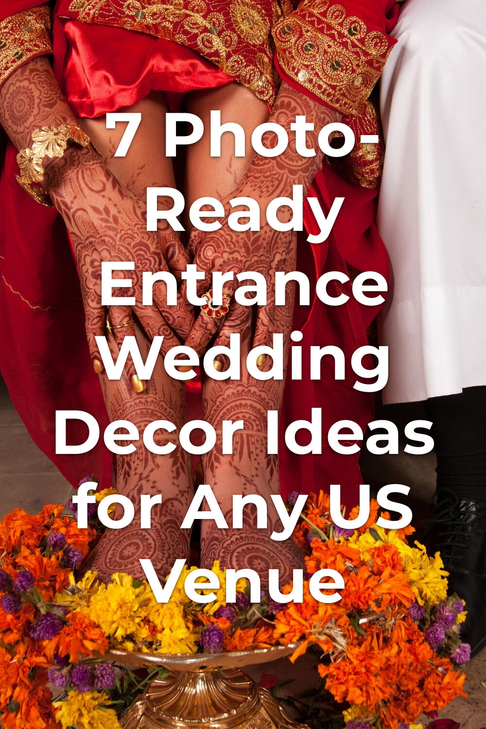entrance wedding decor with henna-covered hands and feet surrounded by orange and yellow flowers