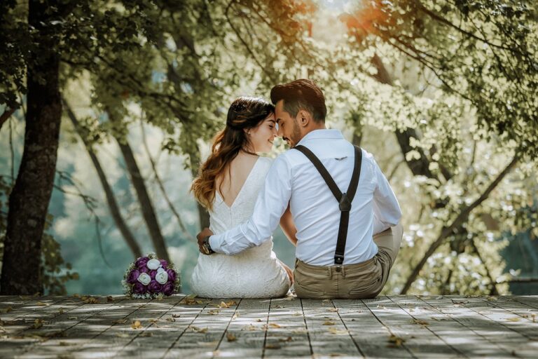 Indian outdoor wedding decor inspiration with couple on wooden deck in forest beside purple and white bouquet