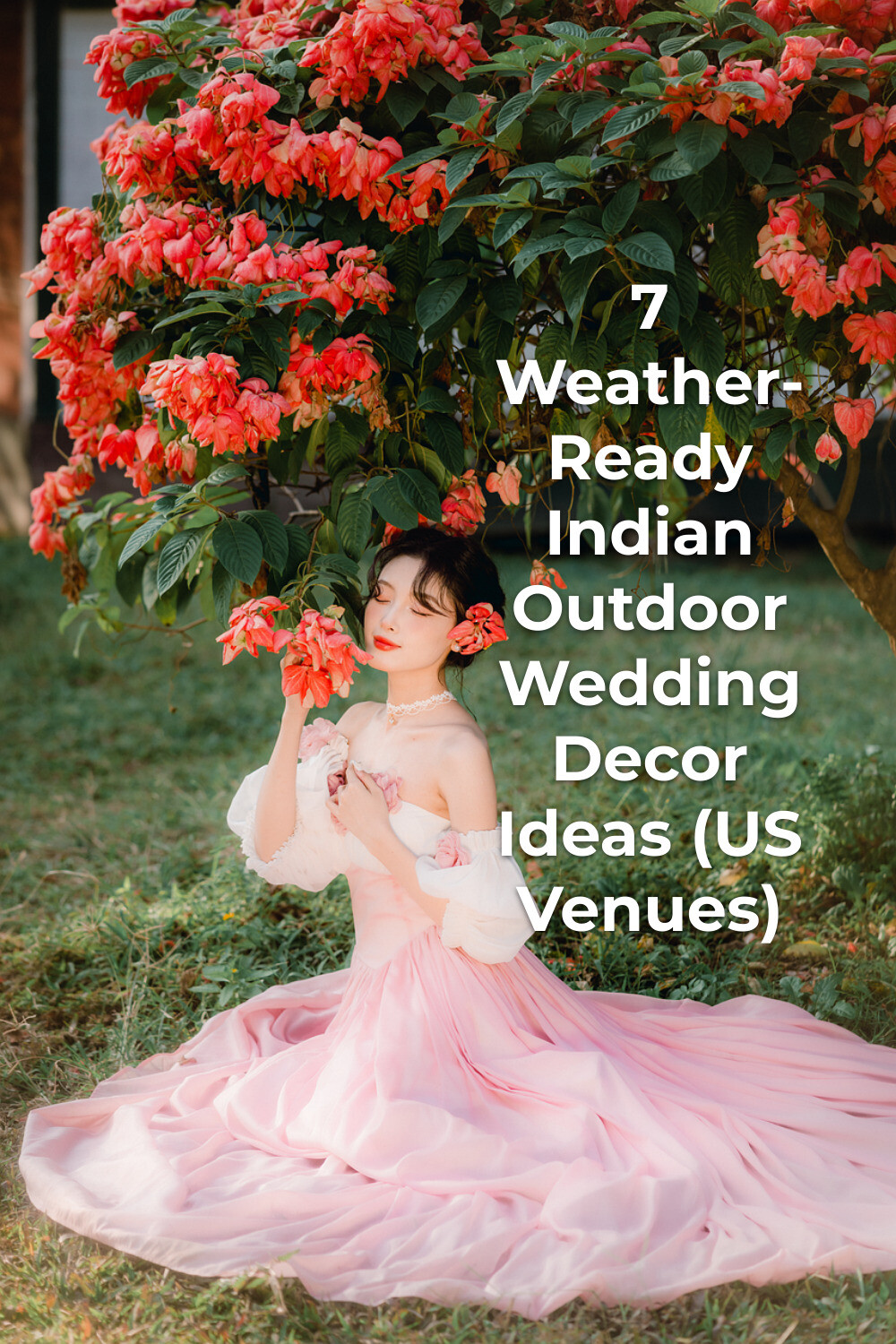 Indian outdoor wedding decor inspiration: woman in pink dress on grass under red-flowered tree holding blooms