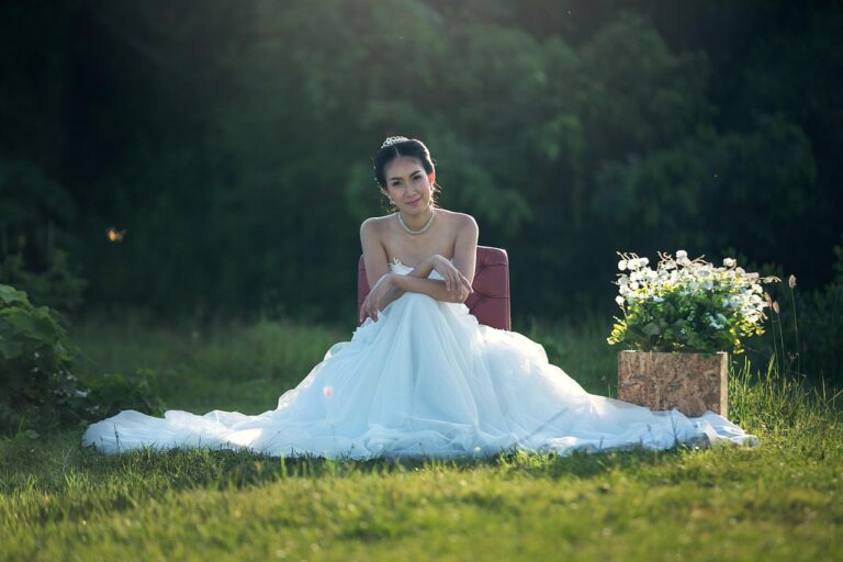 night wedding decor indian inspiration with bride in white dress seated by a box of white flowers in a grassy field