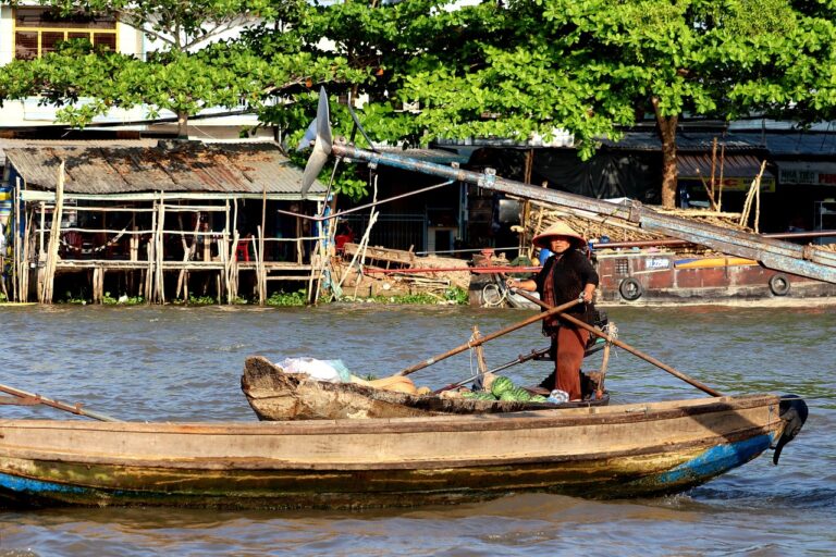 Summer wedding decor inspiration: woman in conical hat on a wooden boat with fresh produce on a riverside