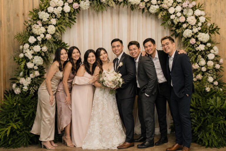 Elegant photo corner wedding setup with soft draped fabric backdrop, florals, and warm lighting for guest portraits