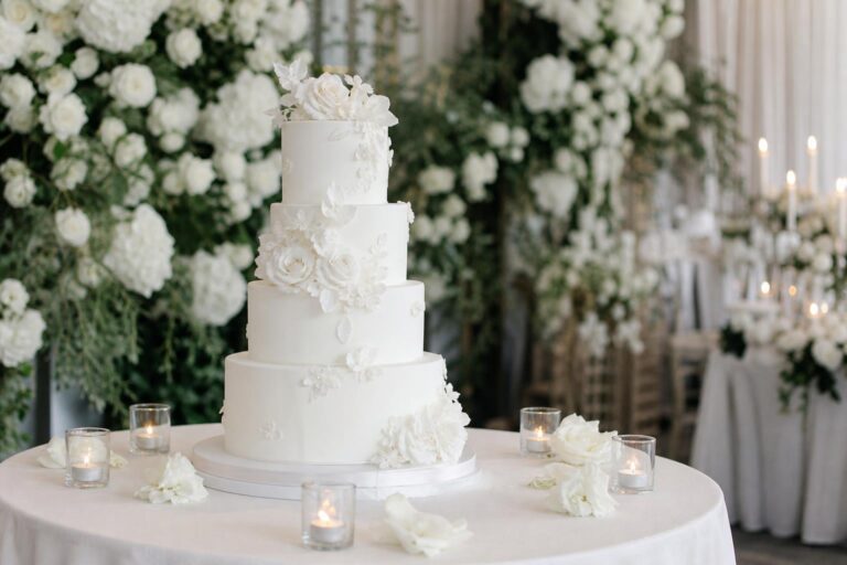 Elegant white wedding cake with smooth fondant tiers and subtle sugar flowers on a modern romantic reception table