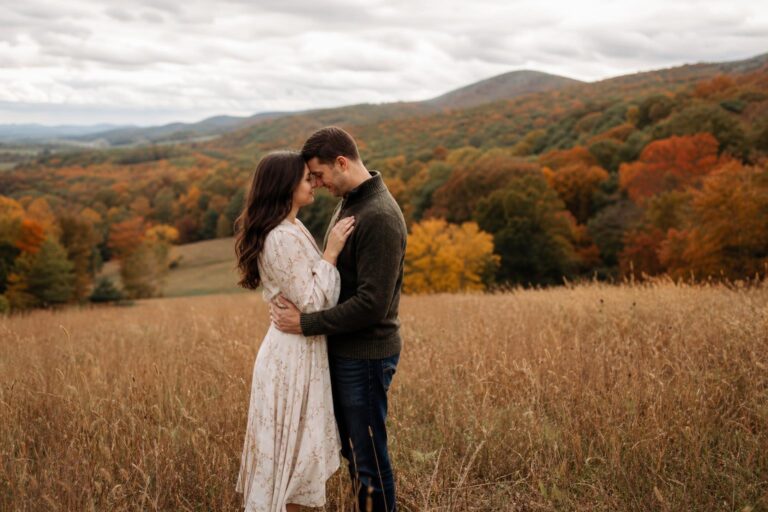 Fall engagement photo outfit ideas with a couple in cozy autumn layers walking through golden leaves in soft light