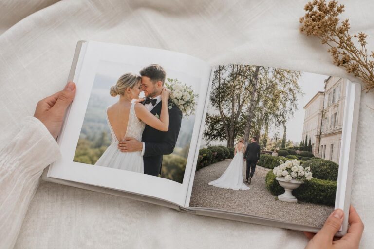 Modern romantic wedding photo book with layflat pages and elegant white cover on a coffee table