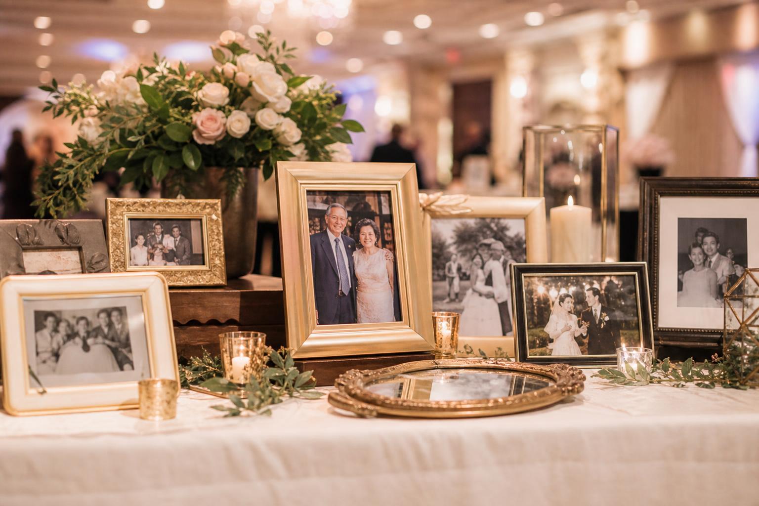 Photo display wedding memory table with framed family pictures, candles, and soft florals in warm reception light