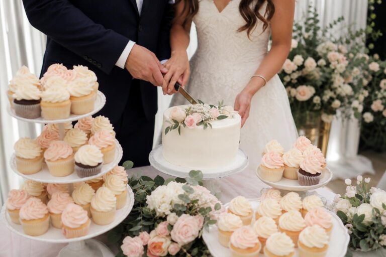 Wedding cake cupcakes with ivory buttercream swirls and fresh floral accents on a tiered dessert stand