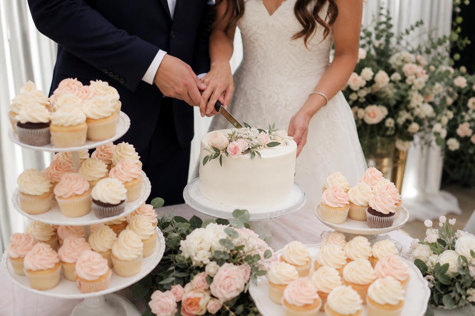Wedding cake cupcakes with ivory buttercream swirls and fresh floral accents on a tiered dessert stand