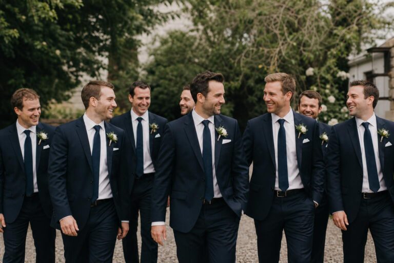 Groomsman photo ideas with groom and groomsmen in suits walking naturally at an elegant wedding venue