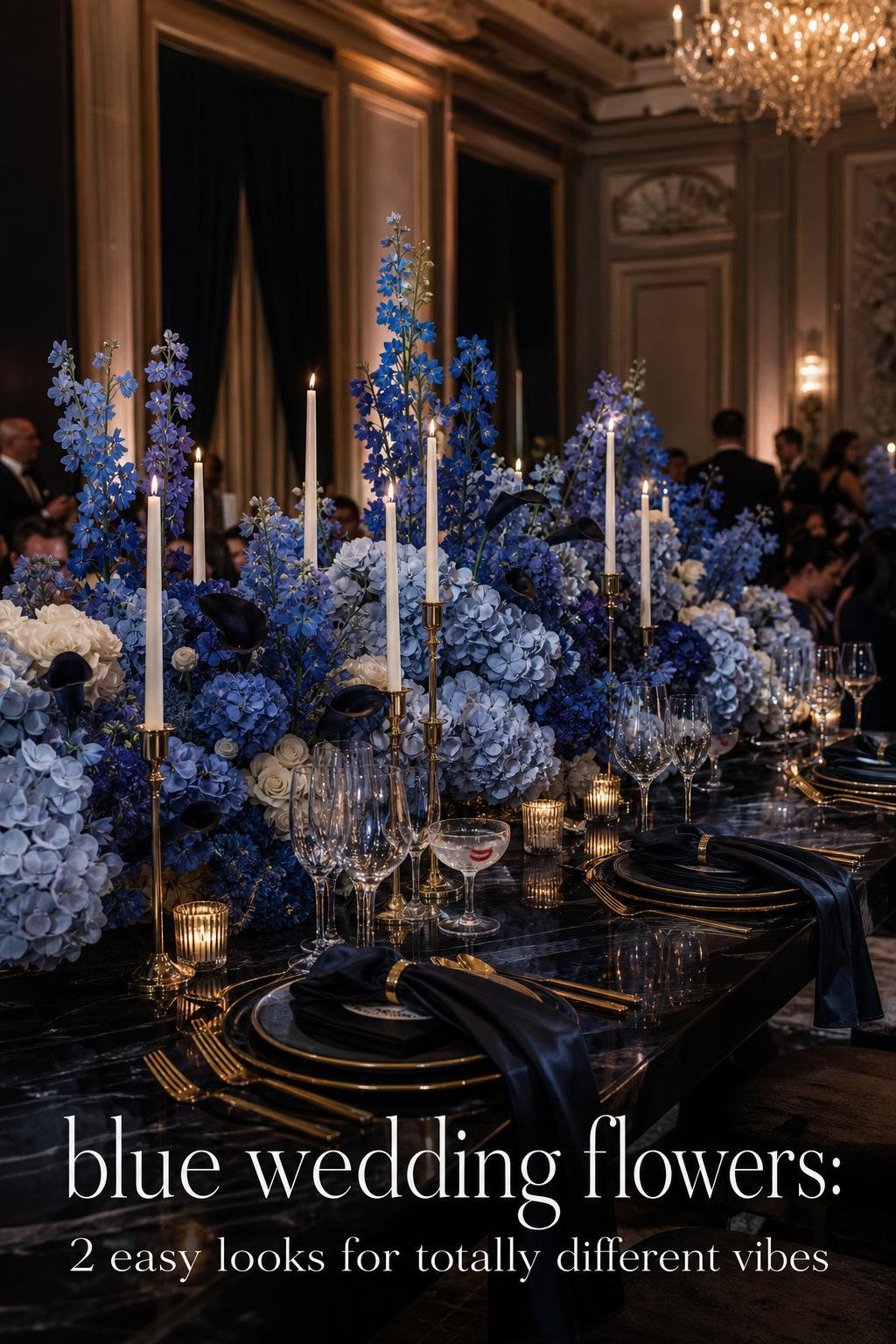 Luxury black-tie reception table with layered blue wedding flowers, ivory candles, crystal glassware, and gold flatware in a ballroom