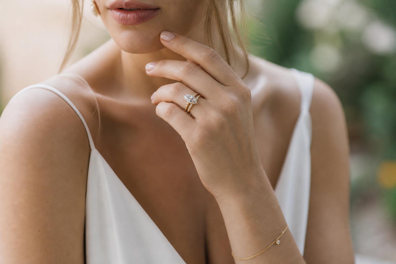 Close-up of a marquise wedding ring on a bride’s hand with elegant natural light