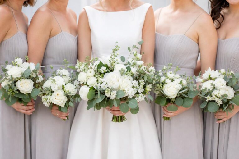 Simple wedding flowers with white roses and greenery on a modern reception table