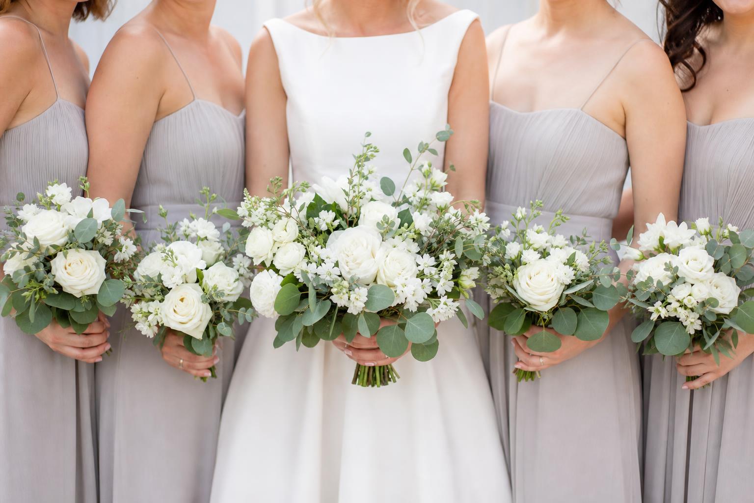 Simple wedding flowers with white roses and greenery on a modern reception table