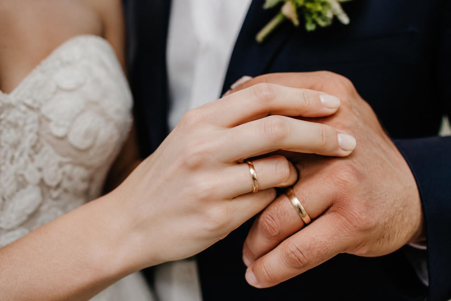 Simple wedding ring in polished yellow gold on a hand, timeless minimalist wedding band in natural light