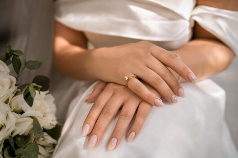 Wedding day nails with glossy pale pink manicure and bridal ring in a romantic modern close-up
